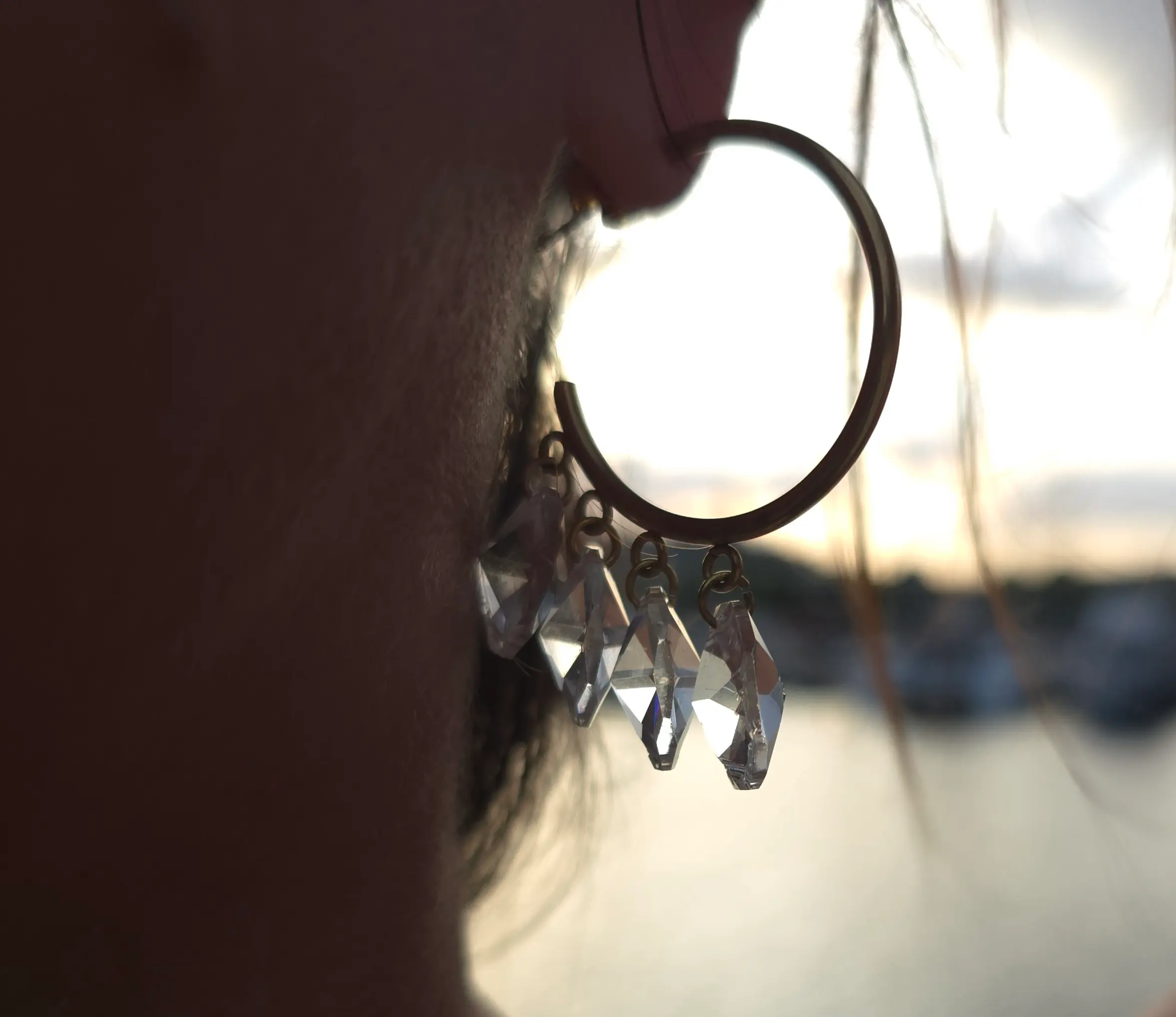 Boucles d’oreilles créoles argentées pampilles diamants transparents brillants contre jour
